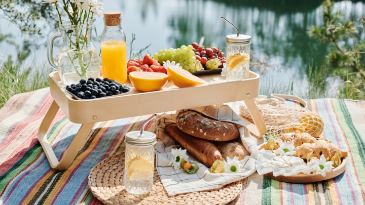 Relaxing outdoor picnic with a beautiful selection of food and drinks, perfect for a sunny day by the water.