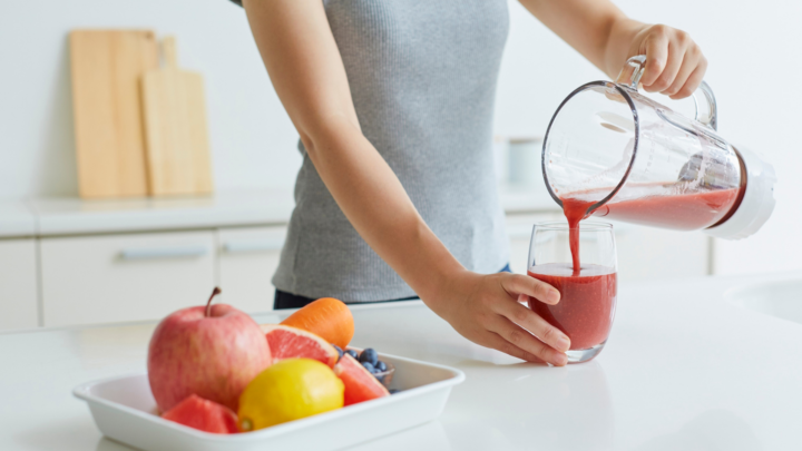 A woman preparing a fruity smoothie
