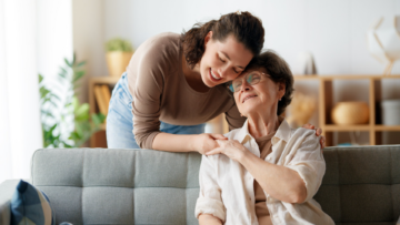 Caregiver fatigue shown with woman leaning on elderly parent.